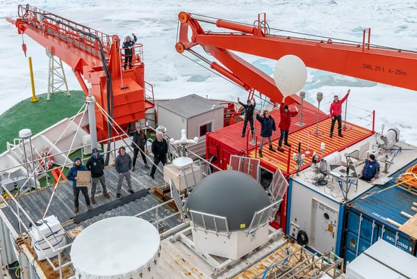 Gruppenfoto des ATMOS-Teams auf dem Vordeck der Polarstern. Rechts unten im Bilder der weiße OCEANET-Container des TROPOS mit unserem Kollegen Martin. Foto: Christian Rohleder, DWD