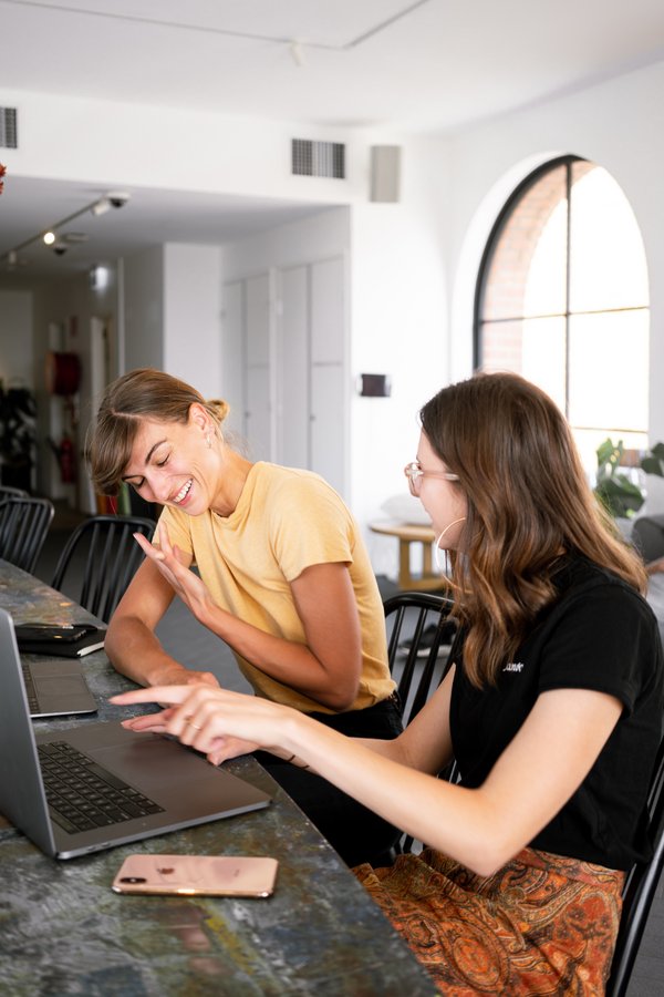 two women working in front of a laptop, laughing