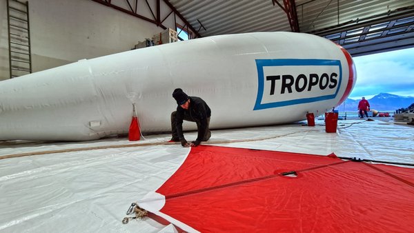 Der Fesselballon BELUGA wird in einem Hangar in Ny-Ålesund für den Aufstieg vorbreitet. Michael Lonardi von der Universität Leipzig montiert das Leitwerk, das den Ballon in der Luft stabilisiert.  Foto: André Ehrlich, Universität Leipzig