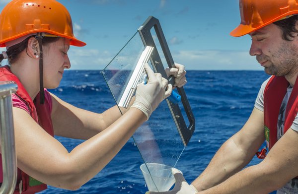For sampling a glass plate is immersed in water and then again carefully pulled out from the water. The 200 micron thin surface film sticks to the glass and is then scraped off with a wiper. (In the photo: Susanne Fuchs and Maik Merkel from the TROPOS dur